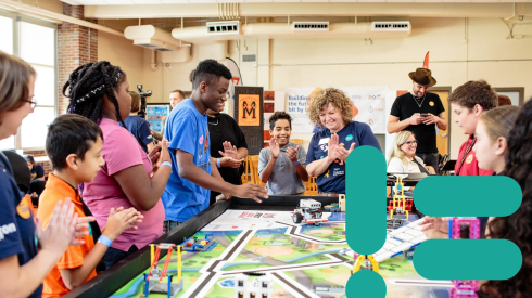 Des collégiens applaudissent un des élèves qui a réussi à faire rouler une voiture automatisée. Un symbole de code vert apparaît à gauche de la photo.